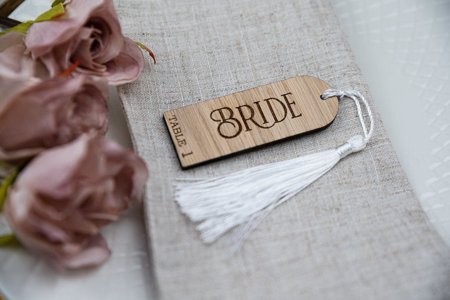 Custom engraved oak wooden place cards with tassels, adding a touch of elegance to any table setting. Personalised with guest&#39;s names, these unique wedding favors double as stylish table decor and guest seating assignments