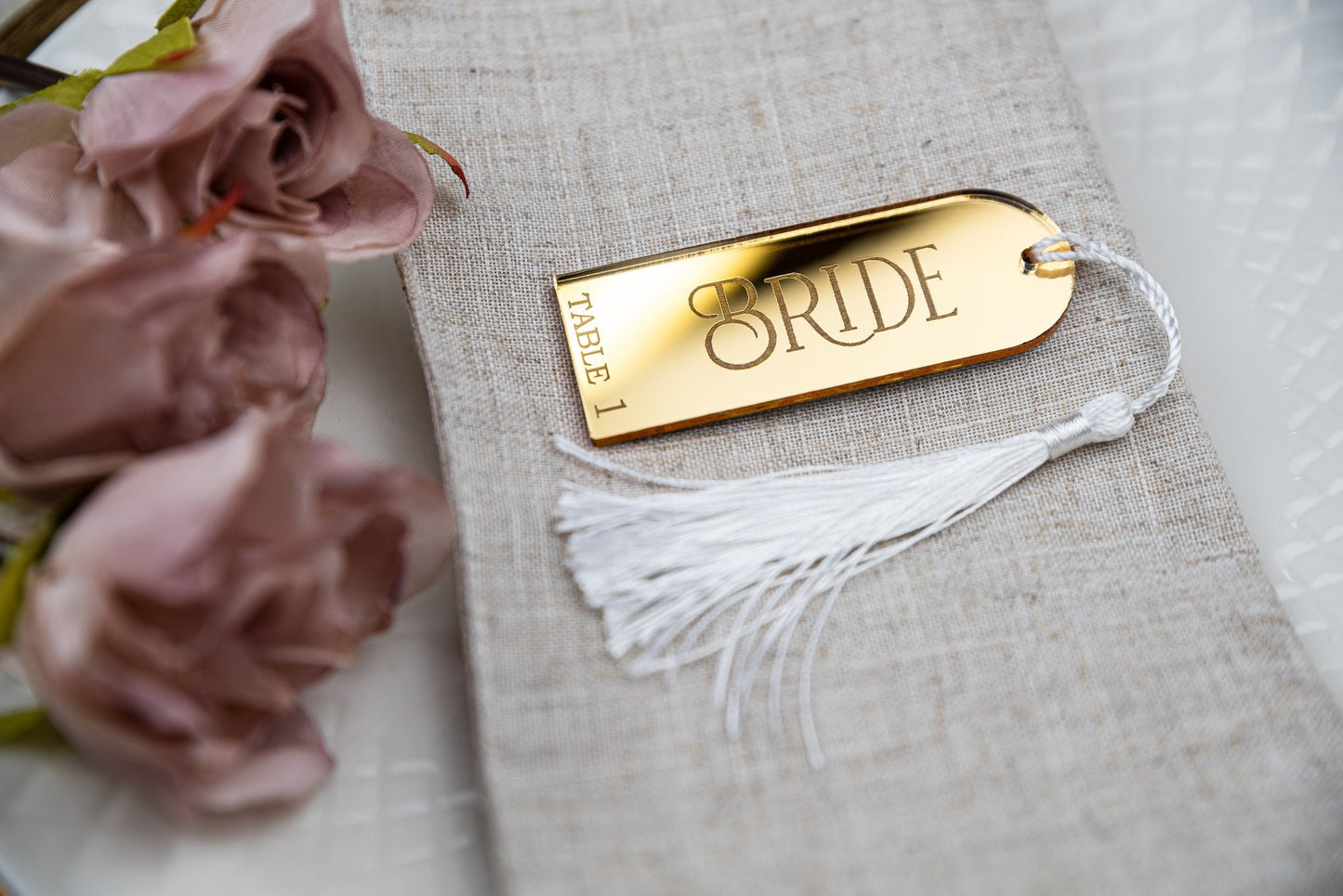 Custom engraved gold mirrored place cards with tassels, adding a touch of elegance to any table setting. Personalised with guest&#39;s names, these unique wedding favors double as stylish table decor and guest seating assignments