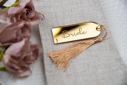 Custom engraved gold mirrored place cards with tassels, adding a touch of elegance to any table setting. Personalised with guest&#39;s names, these unique wedding favors double as stylish table decor and guest seating assignments