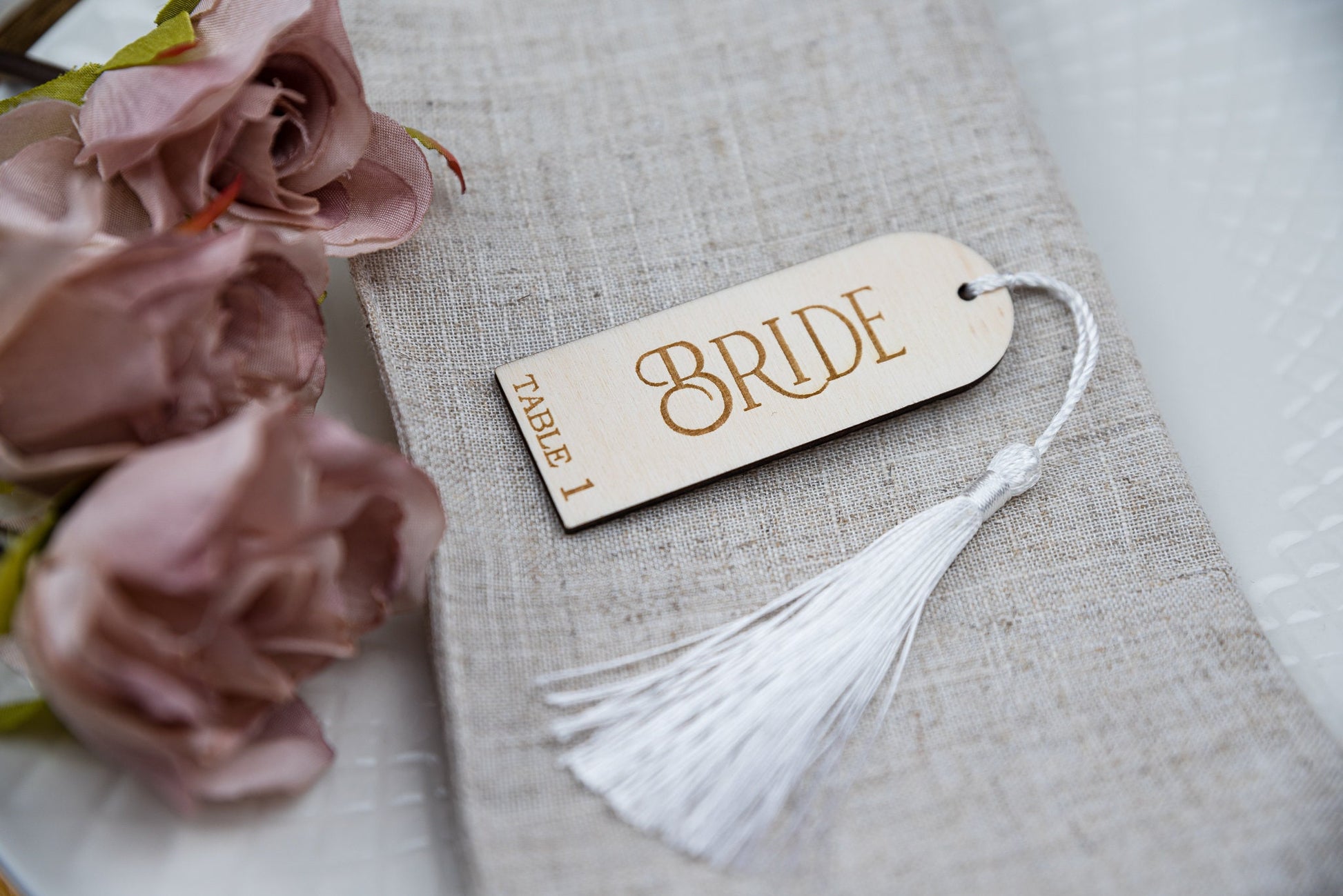 Custom engraved birch ply place cards with tassels, adding a touch of elegance to any table setting. Personalised with guest&#39;s names, these unique wedding favors double as stylish table decor and guest seating assignments